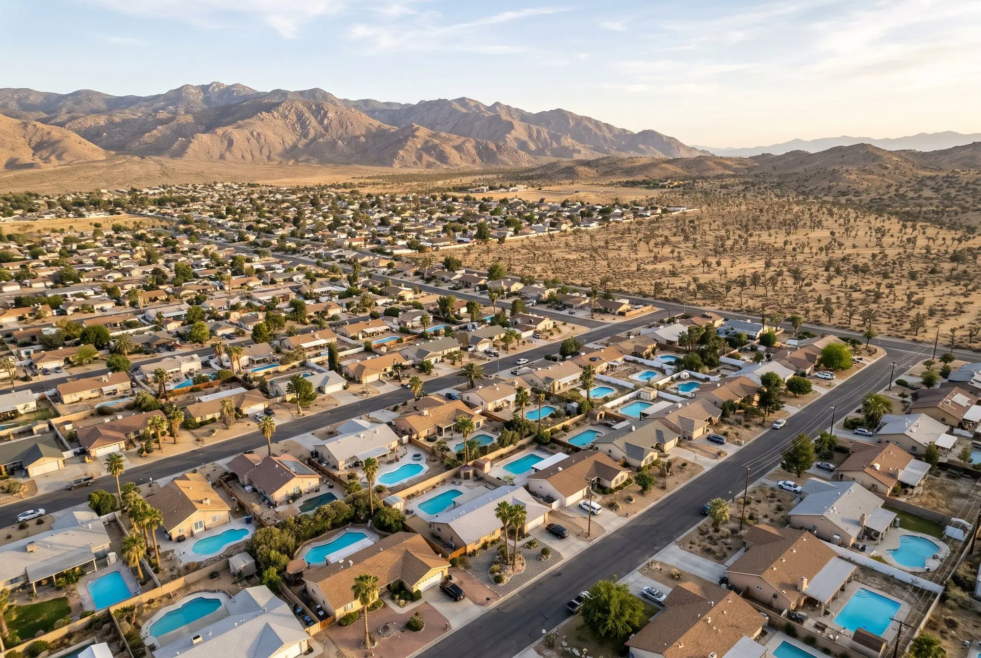 High desert town with backyard pools between the homes and mountains on the horizon