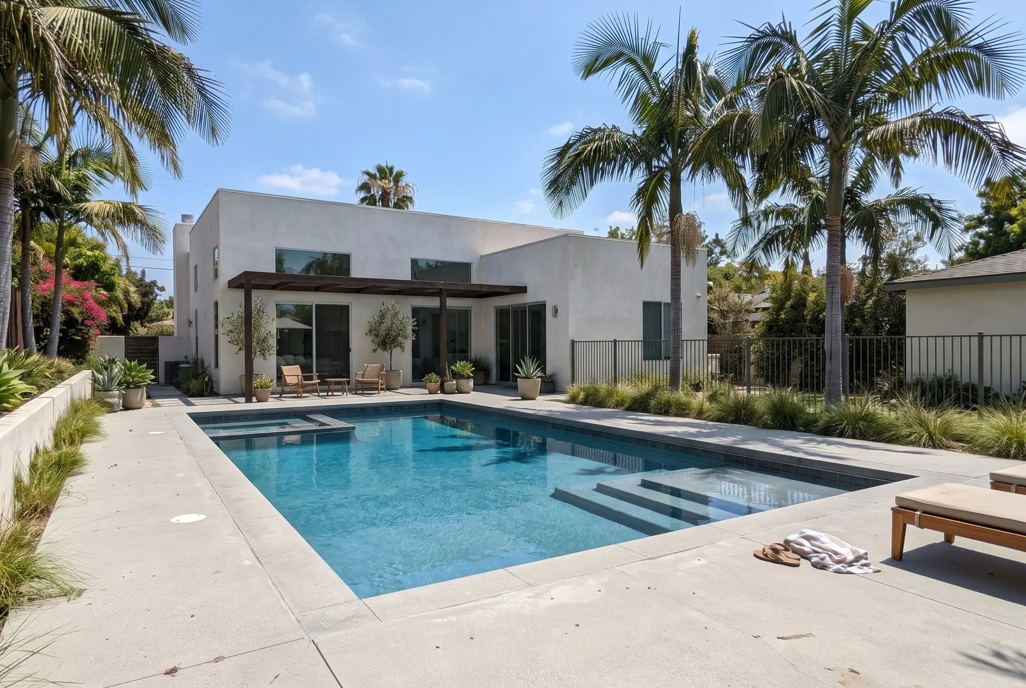 Modern rectangular pool with dark gray tile and tall palm trees