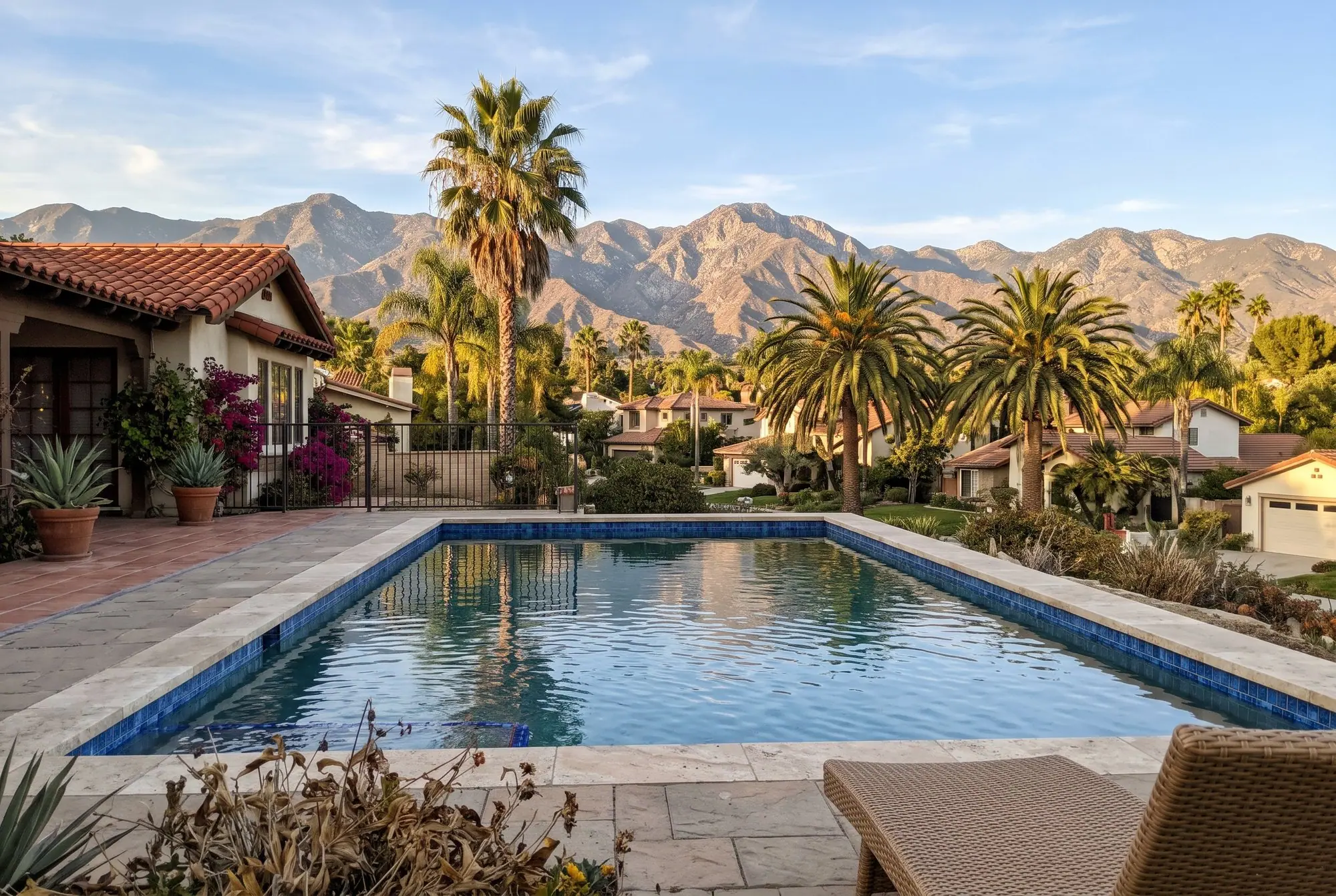 Backyard pool with blue glass tile, palm trees and the mountains behind the neighborhood